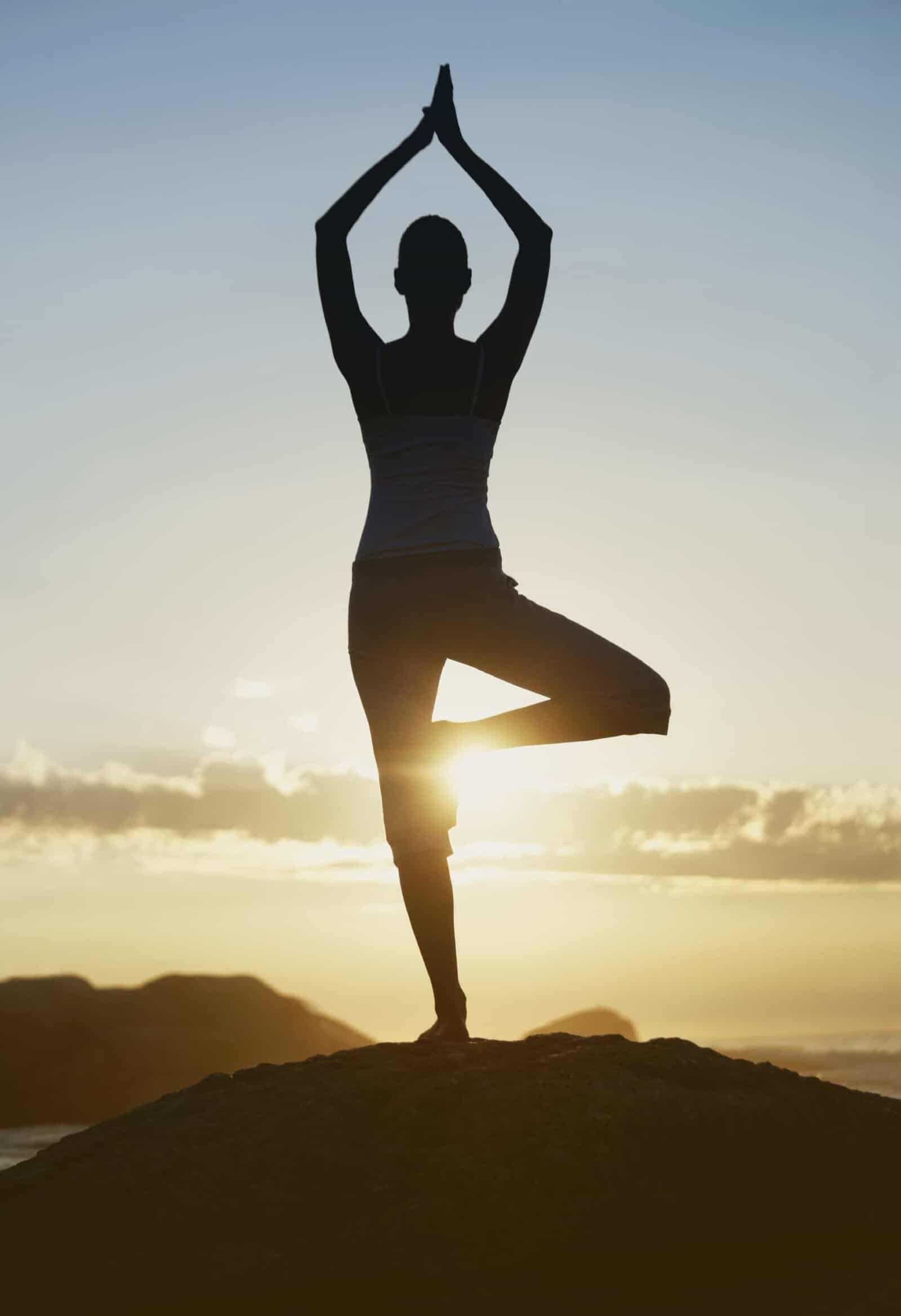 Silhouette of a woman in standing yoga pose at sunset